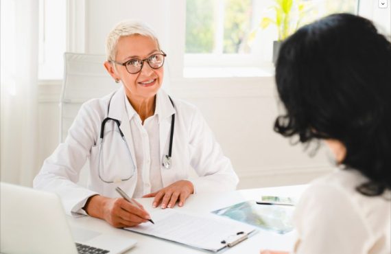 Un médecin avec un stéthoscope pendant un rendez-vous avec une patiente et l'écoute en souriant.